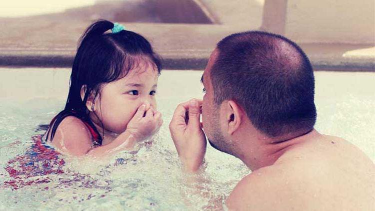 爸爸和女儿一起练习水上安全.